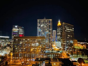 A nighttime cityscape with high-rise buildings, including a prominent skyscraper with a lit top.