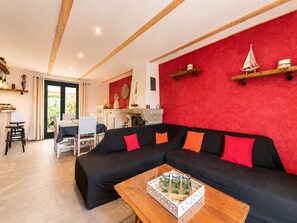 A living room with a black sectional sofa, a wooden coffee table, and a red accent wall.