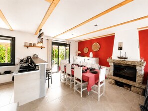 Een moderne keuken met een eethoek, een open haard en uitzicht op groen.