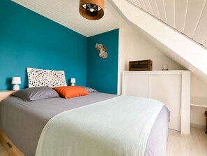 A bedroom with a bed, a white wardrobe, and a ceiling light fixture.