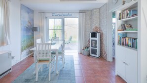 Een eethoek met een tafel, stoelen, een boekenkast en uitzicht op de omgeving.