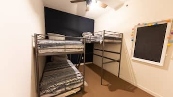 Cozy retreat with a bunk bed arrangement, ceiling fan, and window with colorful decorations.