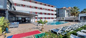 A hotel with a swimming pool, lounge chairs, and a covered entrance. - Blue Port Hotel (Burhaniye)