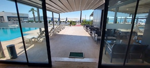A poolside area with lounge chairs and umbrellas, a bar, and a view of the sea. - Blue Port Hotel (Burhaniye)