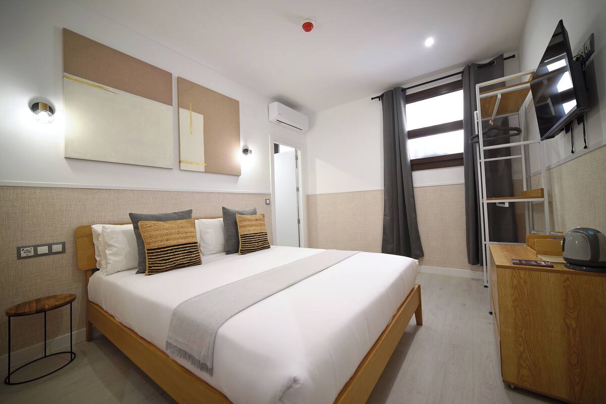 Una habitación de hotel con cama, mesita de noche y escritorio con silla.