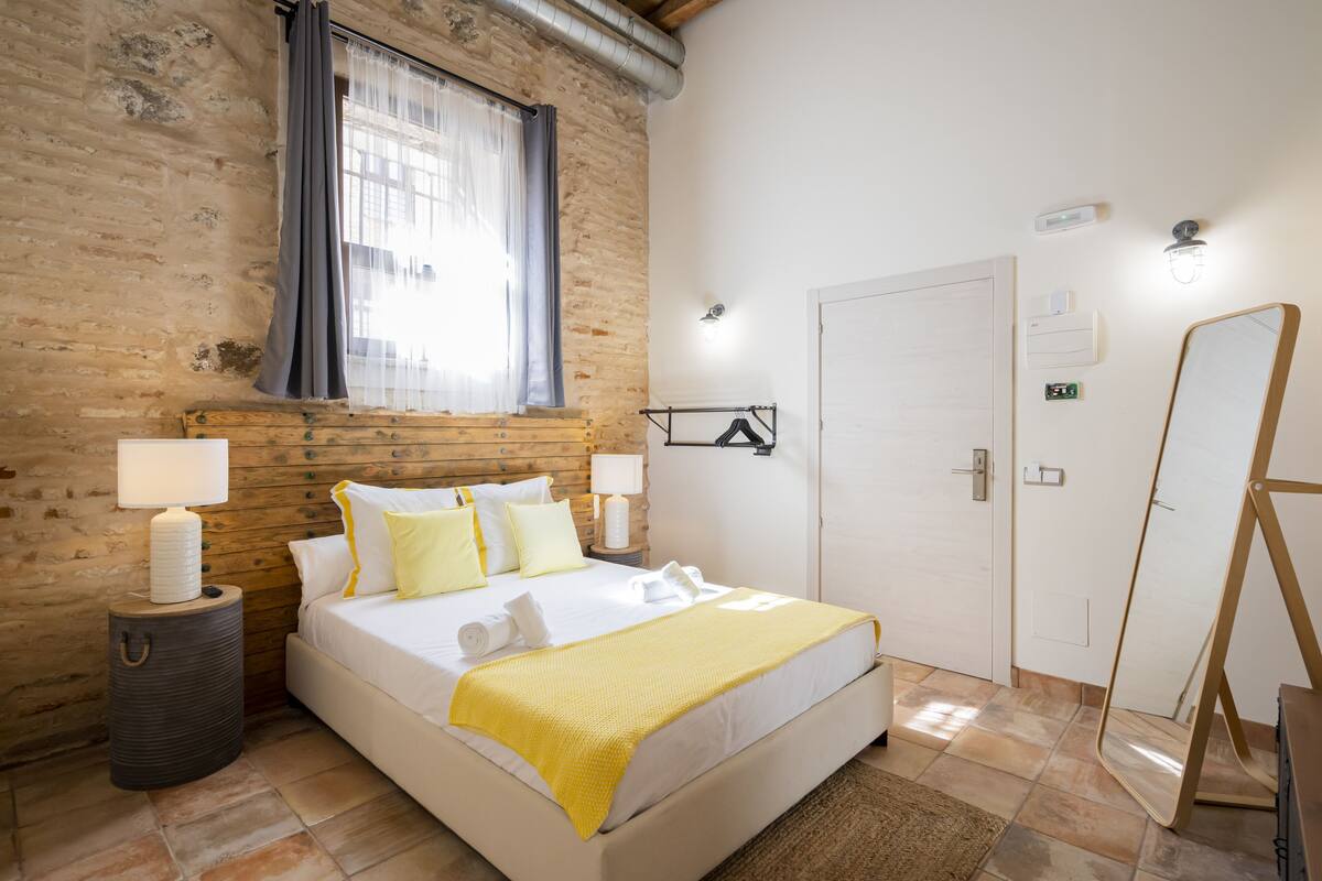 Un dormitorio ordenado con cama, lámparas de noche, un espejo y una puerta.