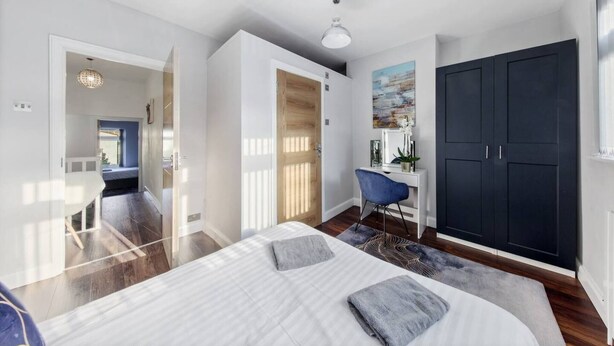 Un dormitorio moderno con una cama grande, un escritorio y un armario.