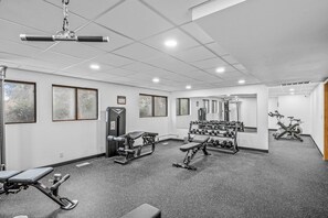A gym with various exercise equipment, including dumbbells, a bench, and a weight machine.