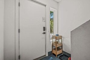 A hallway with a closed door, a small window, and a wicker shelf with baskets.