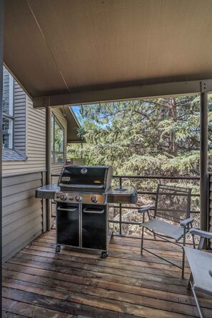 A covered outdoor area with a grill, a chair, and a table.