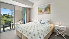 Una camera da letto con un letto grande, un comodino, una scrivania e una sedia. È presente un balcone con vista sull'esterno.