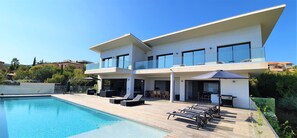 Une maison moderne à deux étages dotée d’une piscine, d’un espace salon extérieur et d’un balcon.