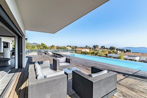 Un espace piscine sur le toit, avec des sièges extérieurs et une vue sur la mer.