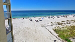A beach with a clear view of the ocean, a sandy shore, and a building with balconies. - Condo in Gulf Shores | Beachfront Views from Private Corner Balcony | Sleeps 8 (Gulf Shores)