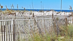 A beach with a wooden fence and a flagpole. - Condo in Gulf Shores | Beachfront Views from Private Corner Balcony | Sleeps 8 (Gulf Shores)