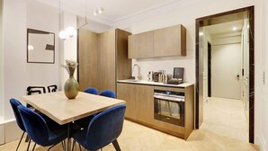 Une cuisine moderne avec des meubles en bois, un four encastré et un coin repas comprenant une table en bois et des chaises bleues.