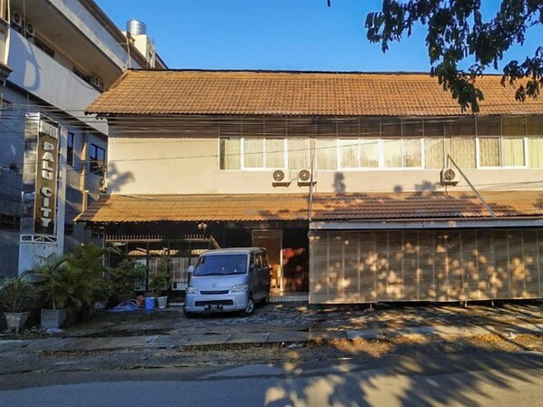 Un edificio a due piani con un garage, un'auto parcheggiata e un cartello con la scritta 'BAIL CITY'.