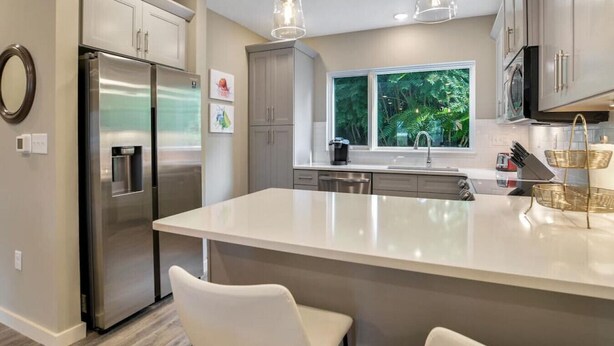 A modern kitchen with a large island, stainless steel appliances, and pendant lighting.