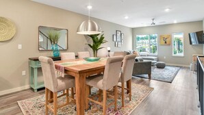 A dining area with a wooden table, beige chairs, and a hanging light fixture.