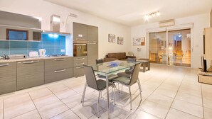 Una cocina moderna con una mesa de comedor de cristal, armarios grises y un horno empotrado.