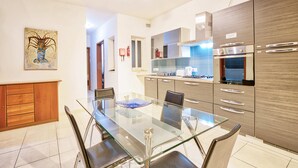 Una cocina moderna con una mesa de comedor de vidrio, electrodomésticos de acero inoxidable y armarios de madera.