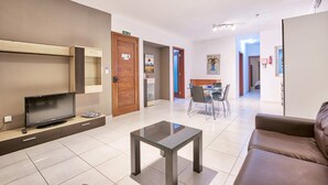 Una sala de estar moderna con un televisor de pantalla plana, una mesa de centro de vidrio y un sofá marrón.