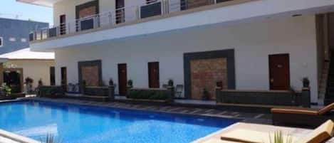 A two-story building with a swimming pool, outdoor seating, and a balcony.