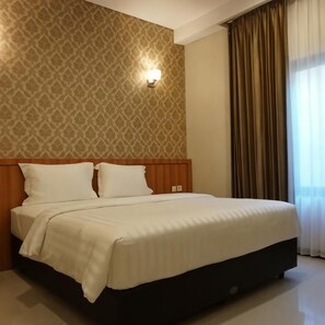 Ein Hotelzimmer mit einem großen Bett, einer Wand mit Muster, einer wandmontierten Lampe und einem Fenster mit Vorhängen.