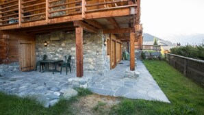 A rustic cabin with a stone exterior, wooden deck, and outdoor seating area. - Bastide 014, Optimal sun exposure, quiet, central location (Verbier)