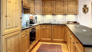A kitchen with wooden cabinets, a black countertop, and a tiled backsplash. - Bastide 014, Optimal sun exposure, quiet, central location (Verbier)