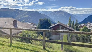 Un paysage montagneux avec un village, des maisons aux toits inclinés et une clôture en bois.