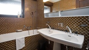 A bathroom with two sinks, a mirror, and a window. - Living room with fireplace, kitchen bar with vitroceram, Nespresso coffeemachine and dishwasher, thr (Verbier)