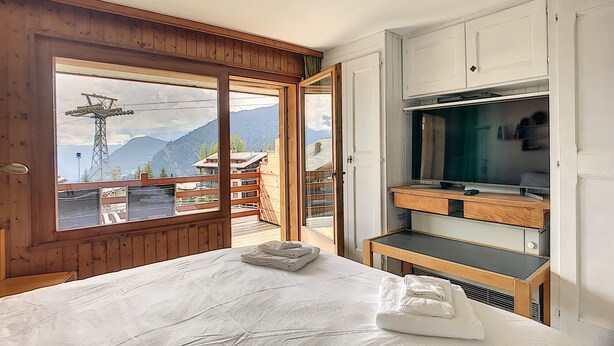Un dormitorio con cama, armario de madera y vista a las montañas.