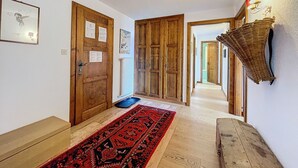 A hallway with wooden doors, a red patterned rug, and a wall-mounted light fixture. - Royal 6, centrally located. Close to shops and restaurants (Verbier)