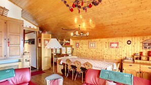 L’intérieur d’un chalet accueillant, avec des murs en bois, une table à manger et des canapés en cuir rouge.