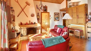 Un salon chaleureux avec une cheminée, un canapé en cuir rouge, des meubles en bois et un plafond en bois.