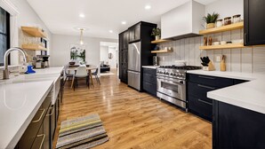A modern kitchen with a central island, wooden flooring, and built-in appliances. - Lakefront Retreat • Hot Tub • 3 Kings + Bunks (Nevada City)