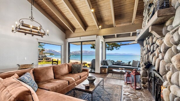 A spacious living area with a stone fireplace, leather sofa, and a view of the sea. - Newly renovated Lake Tahoe Beachfront #635 (South Lake Tahoe)