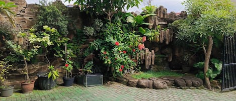 A paved courtyard with potted plants and a stone wall.