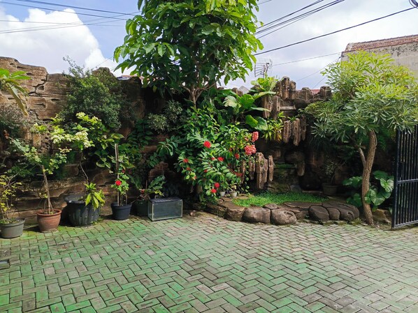 A paved courtyard with potted plants and a stone wall. - Adisa Homestay by Zuzu (Malang)