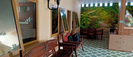 Una habitación con bancos de madera, un ventilador, un reloj de pared y un mural de un paisaje tropical.