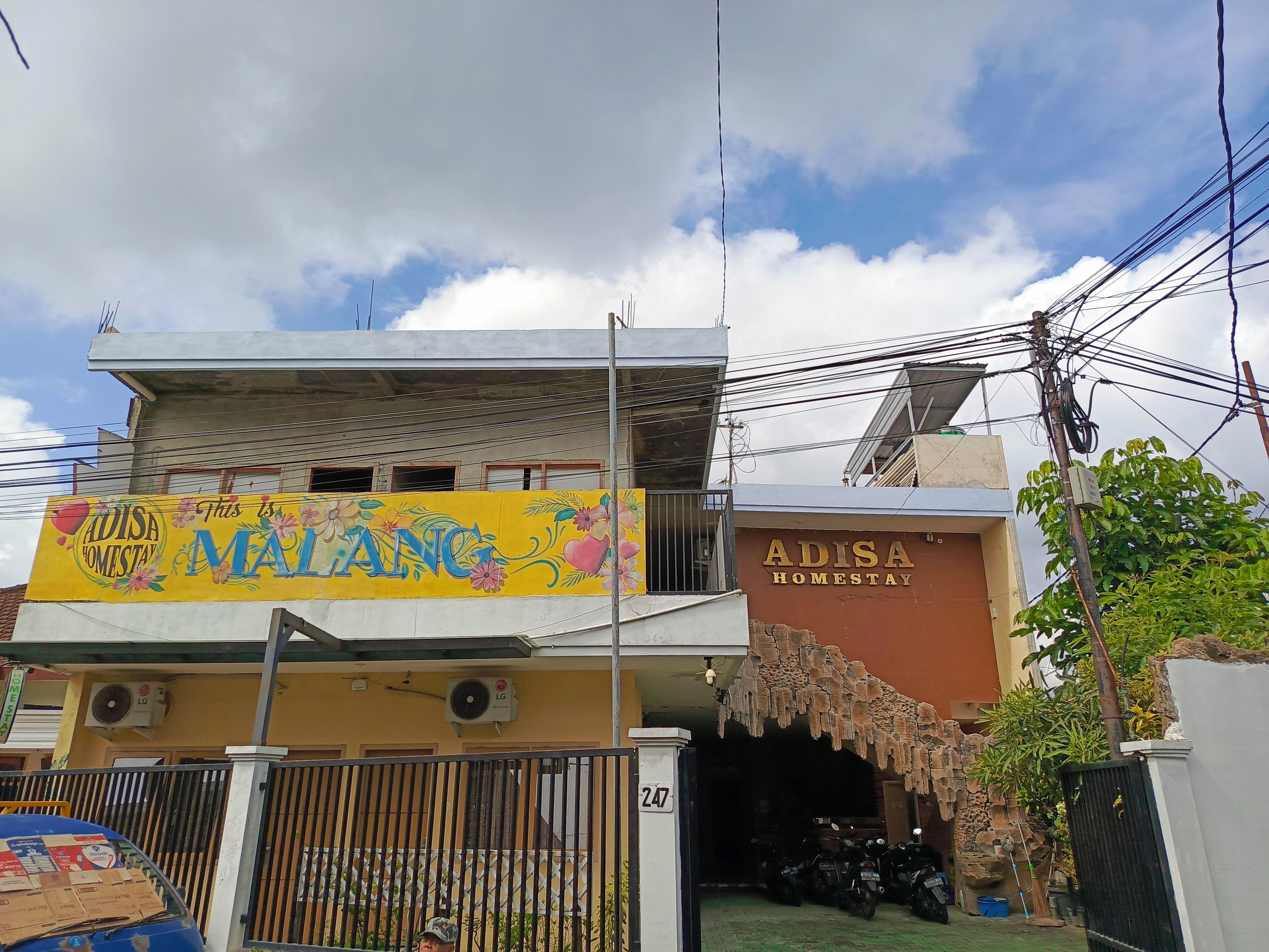 A building with a sign reading 'ADISA HOMESTAY' and a colorful banner above.