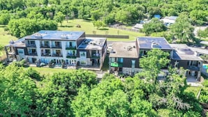 A multi-story residential building with a rooftop terrace, surrounded by lush greenery. - SS B4 Riverside Condo (New Braunfels)