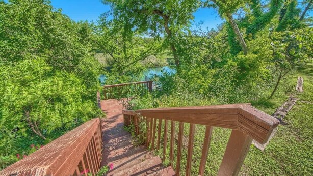 A wooden staircase leading to a natural area with a view of a body of water. - SS B4 Riverside Condo (New Braunfels)