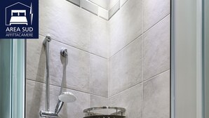 A shower area with a handheld showerhead, a wall-mounted showerhead, and a glass shower tray.