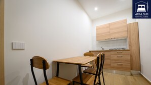 A compact kitchen with wooden cabinets and a dining area with a table and chairs.