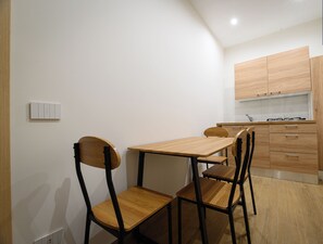 A compact kitchen with wooden cabinets and a dining area with a table and chairs. - South Area Affittacamere (self check-in) Triple room with kitchen (Canicattì)