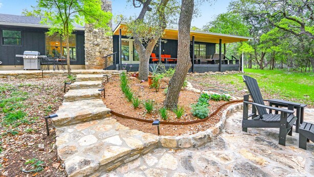 A modern outdoor patio with stone steps, a grill, and Adirondack chairs. - Red Bird Cottage- Convenient 2/1 with Outdoor Space (Wimberley)