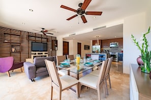 A modern living room with a glass dining table, sofas, and a ceiling fan. - Resort-Style Amenities & Modern Decor (Huatulco)