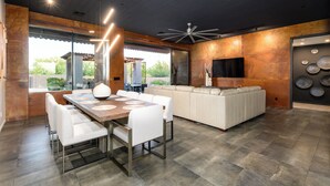 Una cocina moderna con comedor, que cuenta con una isla grande, muebles blancos y un ventilador de techo.